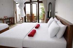a large white bed with two red pillows on it at Amado Homestay Ella in Ella