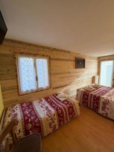 twee bedden in een kamer met houten wanden en ramen bij Albergo Ristorante K2 in Roana