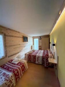 twee bedden in een kamer met houten wanden bij Albergo Ristorante K2 in Roana +44 foto's