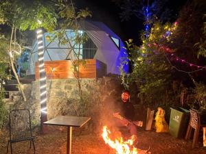 卡绍利Glamp Retreat Kasauli的夜间坐在营火旁的人