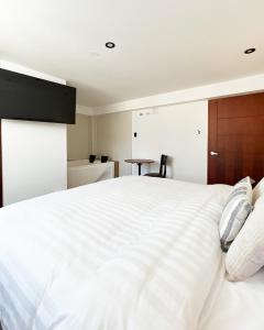 une chambre avec un grand lit blanc et une table dans l'établissement Hostal Llampayec, à Chiclayo