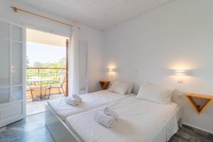 een slaapkamer met een bed met witte lakens en een balkon bij ILENA HOTEL in Acharavi