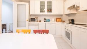 una cucina bianca con mobili e sedie bianchi di Casa Paseo del Tajo Parking Incluido - Living Toledo a Toledo