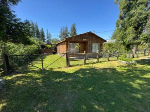 een hek voor een houten huis bij Cabañas Granja Paraíso in Molina