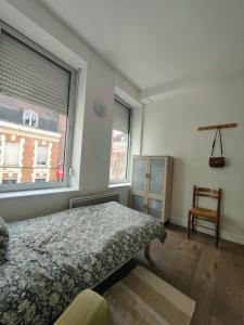 een slaapkamer met een bed, een stoel en een raam bij AB Studio in Roubaix