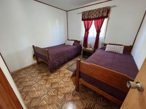 twee bedden in een kleine kamer met rode gordijnen bij Cabañas Granja Paraíso in Molina +43 foto's