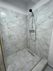 ein Bad mit einer Dusche und weißen Marmorfliesen in der Unterkunft Piata Uniri Cozy Inn in Bukarest