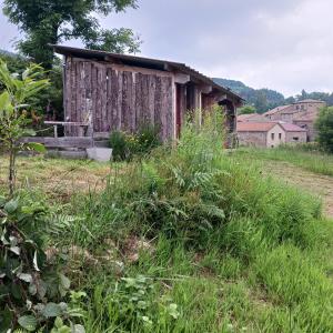 een oude hut in een veld met hoog gras bij Camping à la Ferme de la Marette in Gluiras