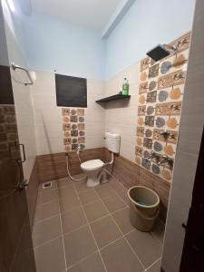 a bathroom with a toilet and a tv on the wall at MUBSS Homestay in Tiruchirappalli