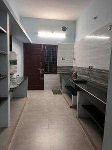 a large kitchen with black counters and a brown door at MUBSS Homestay in Tiruchirappalli