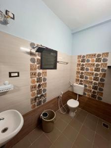 a bathroom with a toilet and a tv on the wall at MUBSS Homestay in Tiruchirappalli