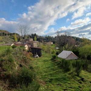 een veld met een schuur en een tent in een veld bij Camping à la Ferme de la Marette in Gluiras