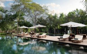 een zwembad met ligstoelen en parasols naast het water bij The Forest in Siem Reap