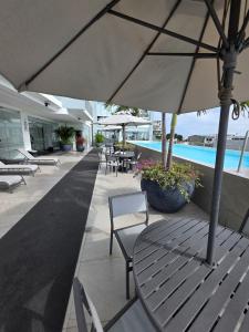 a table and chairs with an umbrella next to a pool at Beautiful Ocean View Apt Salinas Malecon Pier in Salinas