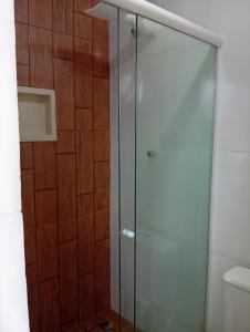 a glass shower in a bathroom with a wooden wall at Cozy house in Matariz Beach in Angra dos Reis +8 photos
