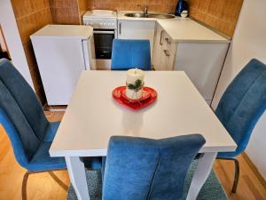 a white table with blue chairs and a candle on it at Apartman Dona in Bosanska Gradiška +7 photos