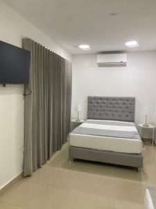 a bedroom with a bed and a flat screen tv at Apartahotel Provenza in Medellín