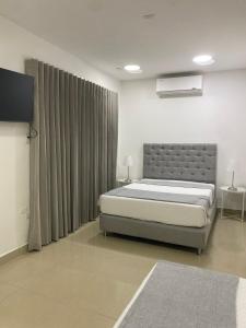 a bedroom with a bed and a flat screen tv at Apartahotel Provenza in Medellín