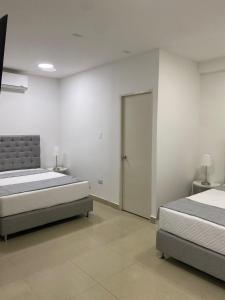 a bedroom with two beds and a sliding door at Apartahotel Provenza in Medellín