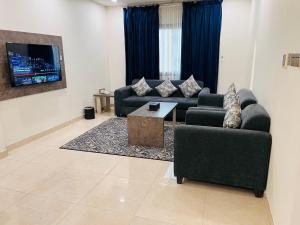 a living room with two couches and a tv at Mabeet Al-Khobar in Al Khobar