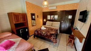 een slaapkamer met een bed en een tafel in een kamer bij Pousada Uluwatu, Praia do Rosa in Praia do Rosa