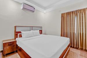 a bedroom with a large white bed and a window at Super Hotel O Royal Suites in Bengaluru