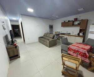 a living room with a couch and a table at Geminado Praia pérola in Passo De Torres +3 photos