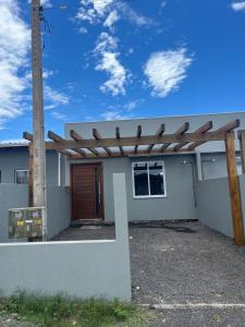 a house with a wooden pergola on it at Geminado Praia pérola in Passo De Torres