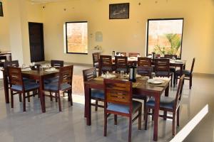 ein Esszimmer mit Holztischen und Stühlen in der Unterkunft Ranthambore Village Serai in Khilchīpur