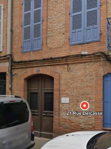 un bâtiment en briques avec une porte et une voiture garée devant dans l'établissement Le Delcassé 1 lit double 1 canapé-lit double, à Montauban