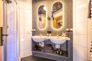 a bathroom with two sinks and two mirrors at Apart Boutiquehotel SONNENHOF in Mayrhofen +67 photos
