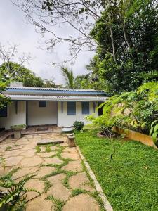 a white house with a garden and a grass yard at Villa Arcadia in Tangalle