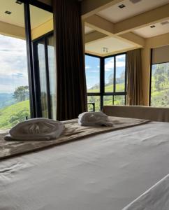 un letto in una camera con ampie finestre di Terraços das Estrelas - Refúgio a 3 km do centro de Gonçalves! a Gonçalves Altre 126 foto