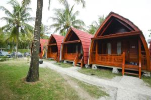 a row of huts with palm trees in the background at Laoceva vila in Padangnegeri