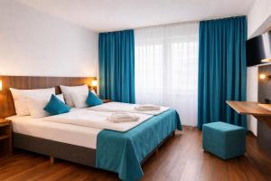 a bedroom with a large bed with blue curtains at Hotel Hansa Stuttgart City in Stuttgart