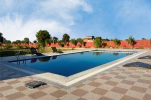 ein großer Swimmingpool mit Stühlen in einem Innenhof in der Unterkunft Ranthambore Village Serai in Khilchīpur