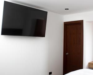 een flatscreen-tv aan de muur van een slaapkamer bij Hostal Llampayec in Chiclayo