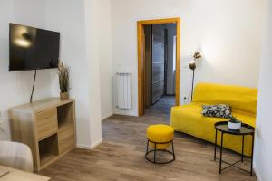 een woonkamer met een geel bed en een tv bij Apartma Castrum Vini in Ajdovščina
