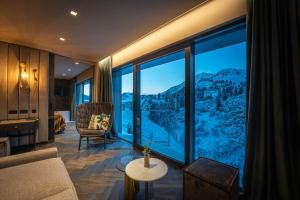 een woonkamer met een groot raam met uitzicht op de bergen bij Das Kohlmayr Superior in Obertauern