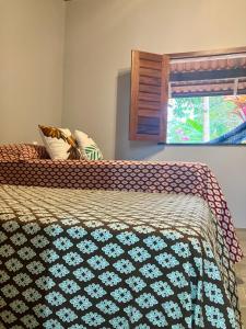 a bed with a blue and white comforter and a window at Sítio casa das fadas em Pacoti in Pacoti