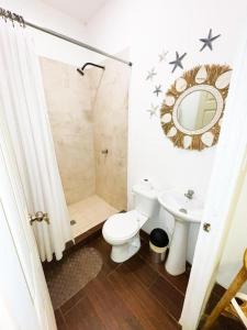une salle de bains avec toilettes, lavabo et miroir dans l'établissement Barú, à La Libertad