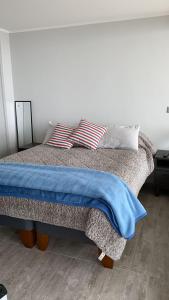 a bed with a blue blanket and two pillows on it at Concón Apartment in Concón