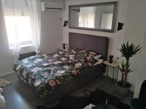 - une chambre dotée d'un lit avec une couette à fleurs et un miroir dans l'établissement HEBRANGOVA Apartman, à Drljanovac