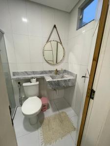 a bathroom with a toilet and a sink and a mirror at Brisa Mar in Canavieiras +9 photos