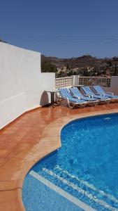 a swimming pool with lounge chairs next to a building at Todosol Dream in Águilas