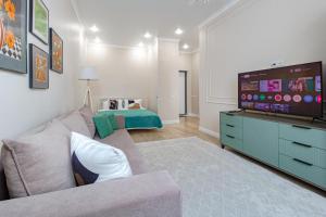 a living room with a couch and a flat screen tv at Мандаринка in Taldykolʼ