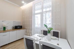 a white kitchen with a table and chairs and a window at Мандаринка in Taldykolʼ