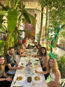 Un groupe de personnes assises à une longue table avec de la nourriture dans l'établissement RIAD LOUDAYA AND SPA, à Fès