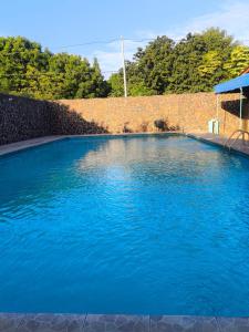 een groot blauw zwembad naast een stenen muur bij Hotel Corazon de Granada in Granada