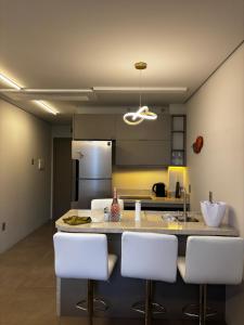a kitchen with a counter with white chairs in it at Loft Livin em Atlântida ao lado do Ramblas in Xangri-lá